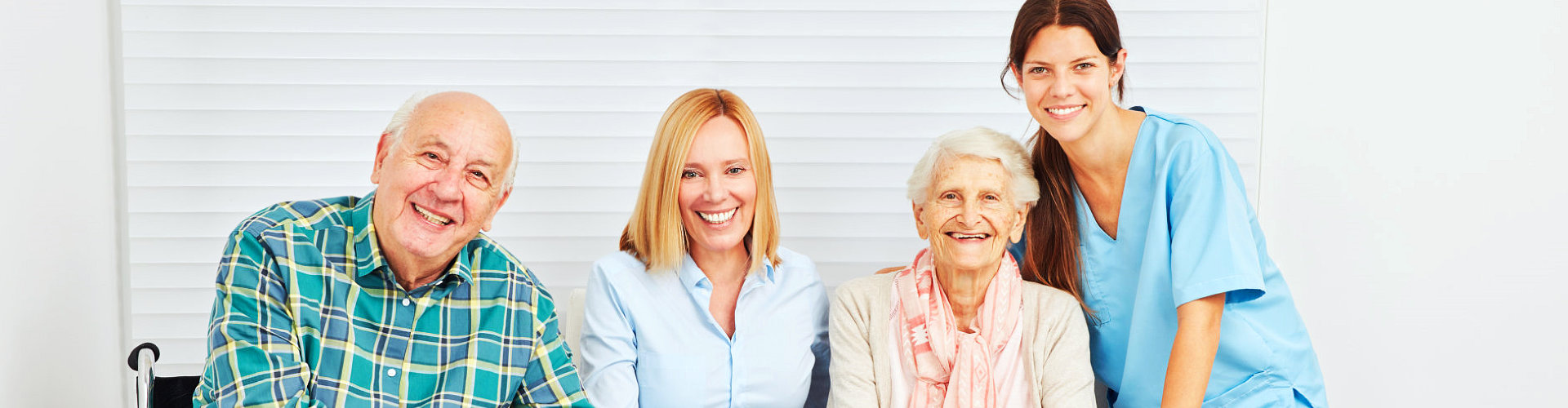 caregivers and an elderly couple smiling at the camera
